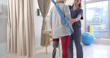 Caucasian female physiotherapist and female senior patient with prosthetic leg exercising. Prosthetics, physiotherapy rehabilitation and medical healthcare concept