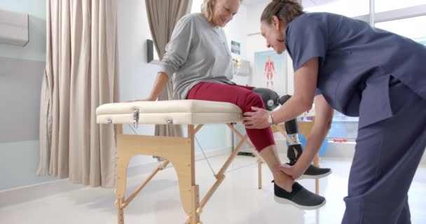Caucasian Female Physiotherapist Stretching Leg Female Patient Rehab Center Prosthetics — Vídeo de stock