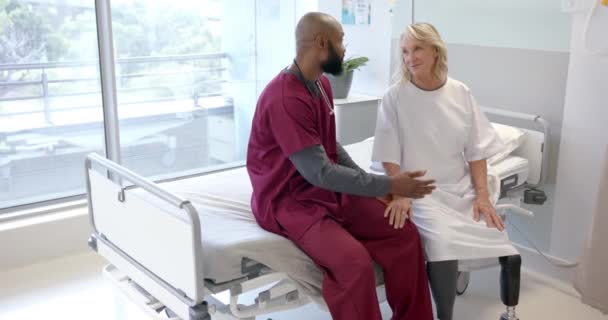 アフリカ系アメリカ人男性医師は 病院で義足を着た白人女性患者と話している プロフェッショナルと医療コンセプト — ストック動画