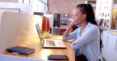 Mutlu Afro-Amerikan iş kadını laptopuyla iş yerinden arıyor, ağır çekimde. İş, iş, iletişim ve günlük ofis, değiştirilmemiş.