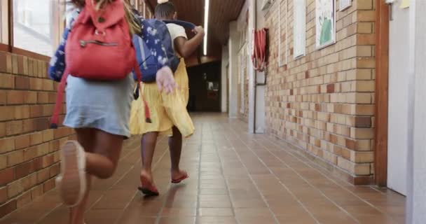 Вид Сзади Счастливых Разнообразных Школьниц Школьными Сумками Бегающими Коридоре Начальной — стоковое видео