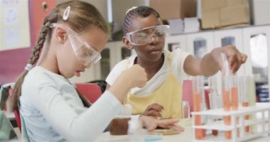 İlkokulda laboratuvarda yavaş çekimde deneyler yapan farklı okullu kızlar. Okul, bilim ve eğitim, değiştirilmemiş.