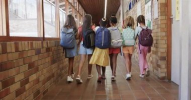 İlkokulun koridorunda okul çantalı mutlu okul kızlarının arka görüntüsü. Okul, eğitim ve eğitim, değiştirilmemiş..