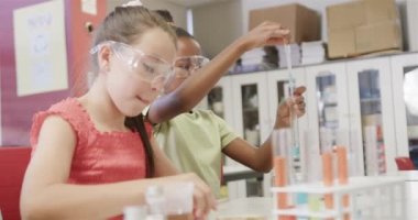 İlkokulda laboratuvarda yavaş çekimde deneyler yapan farklı okullu kızlar. Okul, bilim ve eğitim, değiştirilmemiş.