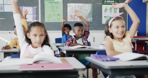 Boldog Változatos Iskolások Asztaloknál Akik Felemelik Kezüket Általános Iskola Osztálytermében — Stock videók