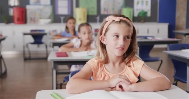 快乐多样的女生坐在课桌前 在小学课堂上举手致意 学习和教育 — 图库视频影像