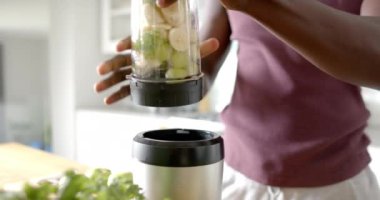 Afrika kökenli Amerikalı bir adamın evde sağlıklı bir içecek hazırlaması, ağır çekimde. Yaşam tarzı, sağlıklı yaşam, yemek ve ev hayatı..