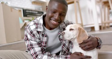 Evcil köpeğiyle merdivenlerde oturan mutlu Afro-Amerikan bir adamın portresi, ağır çekimde. Yaşam tarzı, evcil hayvanlar ve ev hayatı, değişmemiş..