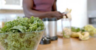 Afrika kökenli Amerikalı bir adamın evde sağlıklı bir içecek hazırlaması, ağır çekimde. Yaşam tarzı, sağlıklı yaşam, yemek ve ev hayatı..