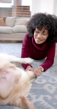 Evde köpekle oynayan melez bir kadının dikey videosu, yavaş çekim. Yaşam tarzı, hayvan, arkadaşlık ve aile hayatı, değişmedi..