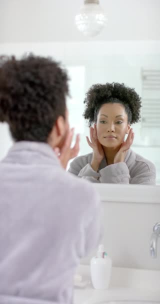 バスルームの鏡を見ている浴室の女性の垂直ビデオ ゆっくりとした動き ライフスタイル セルフケア 家庭生活 変わらない — ストック動画