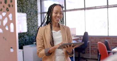 Afro-amerikan iş kadını tablet kullanıyor ve ofiste konuşuyor. Günlük ofis, iş, iletişim ve iş, değiştirilmemiş.