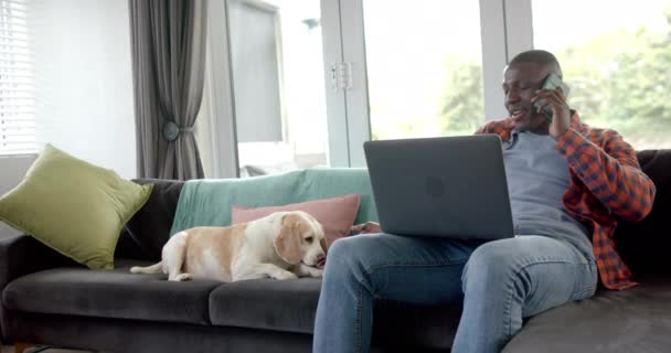 Africano Americano Falando Smartphone Usando Laptop Casa Com Seu Cão — Vídeo de Stock