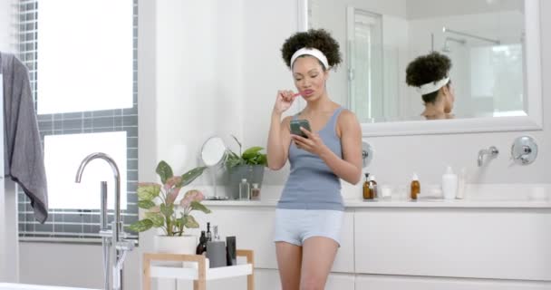 Happy Biracial Woman Brushing Teeth Using Smartphone Bathroom Slow Motion — Stock Video