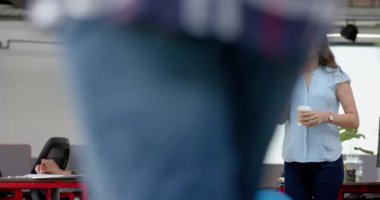 Kafkasyalı iş kadını elinde kahve fincanıyla ofiste yürürken telefonla konuşuyor. İş, teknoloji ve ofis kavramı