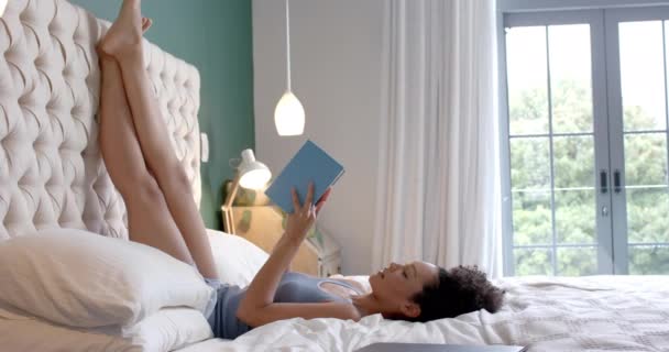 Çift Irklı Bir Kadın Yatakta Uzanıyor Yatak Odasında Kitap Okuyor — Stok video