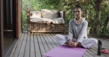 Terasta yoga yapan çift ırklı kadın, fotokopi aletiyle ağır çekim. Yaşam tarzı, doğada refah, yoga, sağlıklı yaşam tarzı, fitness ve ev hayatı, değişmemiş.