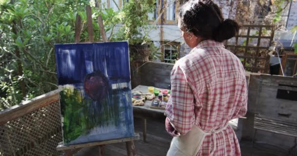 日当たりの良い庭でスマートフォンを使用して彼女の絵画の写真を撮る白人女性アーティスト ゆっくりとした動き ライフスタイル クリエイティビティ アート コミュニケーション 家庭生活 — ストック動画