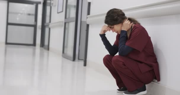 Κουρασμένη Καυκάσια Γιατρός Που Κάθεται Στο Διάδρομο Του Νοσοκομείου Αργή — Αρχείο Βίντεο