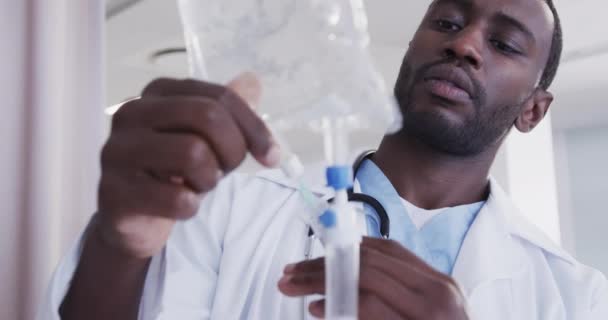 アフリカ系アメリカ人の男性医師が病院の部屋でドリップをチェックし 動きが遅い メディカルサービス 変わらない — ストック動画