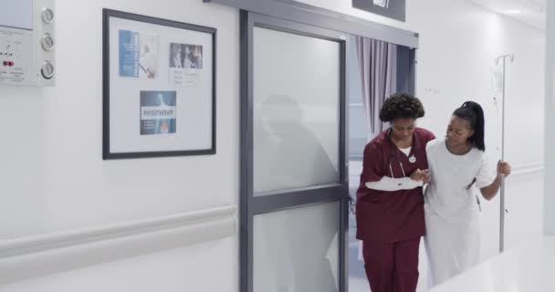 Африканская Американка Врач Помогает Пациентке Ходить Больничному Коридору Замедленная Съемка — стоковое видео