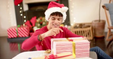 Çift ırklı bir adam Noel hediyesini dekoratif bir kağıda sarıyordu, ağır çekimde. Yaşam tarzı, Noel, kutlama, hediye ve ev hayatı, değişmemiş..