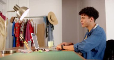 Çift ırklı erkek moda tasarımcısı. Stüdyoda dizüstü bilgisayar kullanarak çizim yapıyor. Ağır çekimde. Moda, tasarım, yaratıcılık, giyim, teknoloji, iletişim ve küçük işletmeler, değiştirilmemiş.