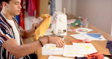 Çift ırklı erkek moda tasarımcısı stüdyoda kıyafet tasarlıyor, ağır çekimde. Moda, tasarım, yaratıcılık, giyim ve küçük işletmeler, değiştirilmemiş.