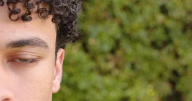 Çift ırklı bir adam yüzünü kapar ve dışarıdaki kameraya bakar, ağır çekimde. Erkeklik, doğa, kaplama ve açık hava, değiştirilmemiş.