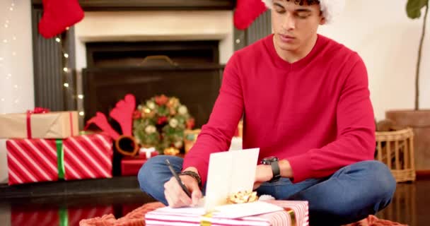 Biracial Hombre Escribiendo Saludos Navidad Tarjeta Navidad Casa Cámara Lenta — Vídeos de Stock
