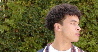 Açık havada çitin önünde duran melez bir adam. Yavaş hareketli fotokopi alanı. Erkeklik, doğa, bitki ve açık hava, değiştirilmemiş.