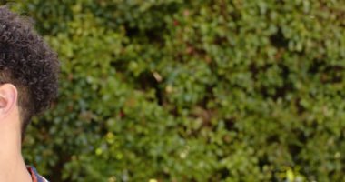 Açık havada çitin önünde gülümseyen melez bir adam, ağır çekim, kopyalama alanı. Erkeklik, doğa, bitki ve açık hava, değiştirilmemiş.