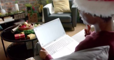 Mutlu Afro-Amerikalı adam evinde video görüşmesi için bilgisayarı kullanıyor, yavaş çekim. Yaşam tarzı, iletişim, noel, kutlama ve ev hayatı, değişmemiş.