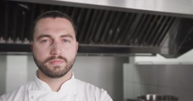 Mutfakta gülümseyen, fotokopi çeken, ağır çekimde gülümseyen beyaz erkek şefin portresi. Aşçılık, meslek, yemek, restoran ve catering, değiştirilmemiş.