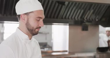 Mutfakta gülümseyen, fotokopi çeken, ağır çekimde mutlu sakallı beyaz erkek şefin portresi. Aşçılık, meslek, yemek, restoran ve catering, değiştirilmemiş.
