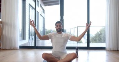Çift ırklı bir adam evde yoga yapıyor ve meditasyon yapıyor, ağır çekimde. Yaşam tarzı, rahatlama, kişisel bakım ve ev hayatı, değişmemiş..