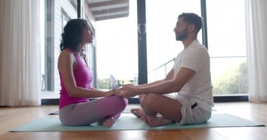 Çift ırklı çift evde yoga yapıyor ve yavaş çekimde meditasyon yapıyor. Yaşam tarzı, rahatlama ve ev hayatı, değişmemiş..
