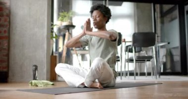 Afrika kökenli Amerikalı adam yoga yapıyor ve evde meditasyon yapıyor, ağır çekimde. Yaşam tarzı, rahatlama, kişisel bakım ve ev hayatı, değişmemiş..