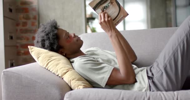 Homem Afro Americano Com Manchas Debaixo Olho Lendo Livro Sofá — Vídeo de Stock