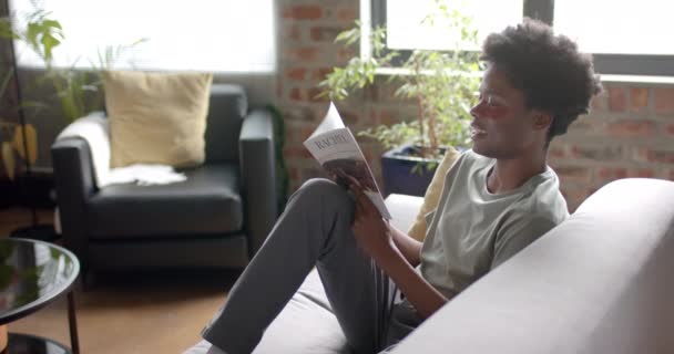 Afrikansk Amerikansk Mann Med Øynene Lesebok Sofa Hjemme Sakte Bevegelse – stockvideo