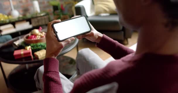 ハッピーアフリカ系アメリカ人男性は 自宅でのビデオ通話のためのコピースペースでスマートフォンを使用して 遅い動き ライフスタイル コミュニケーション クリスマス お祝い 家庭生活 — ストック動画
