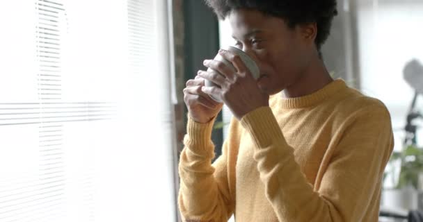Omtenksom Afrikansk Amerikansk Mann Som Drikker Kaffe Ser Gjennom Vinduet – stockvideo