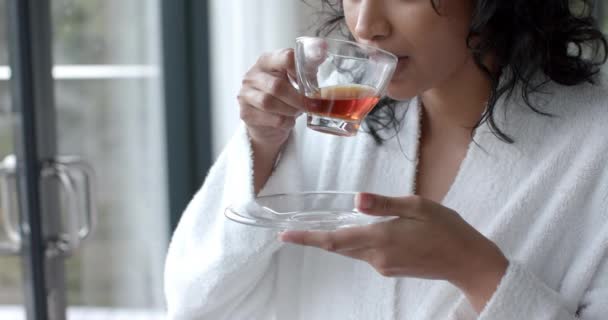 Mulher Biracial Vestindo Roupão Banho Bebendo Chá Olhando Pela Janela — Vídeo de Stock