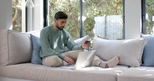 Biracial Homem Sentado Sofá Usando Laptop Para Compras Line Casa — Vídeo de Stock