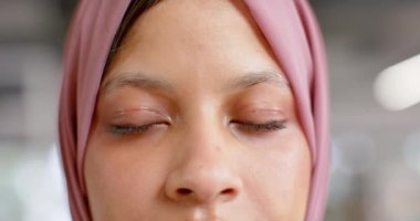 Ofisteki tesettürlü, çift ırklı iş kadınının mutlu gözlerinin portresi, ağır çekim. Günlük ofis, iş ve iş, değiştirilmemiş.