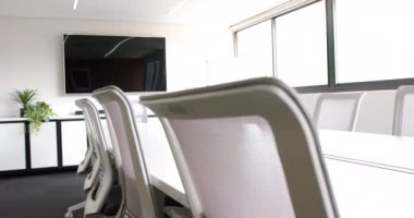 Masası, sandalyeleri ve ekranı olan güneşli toplantı odası, yavaş çekim. Günlük ofis, iş, iletişim ve iş, değiştirilmemiş.