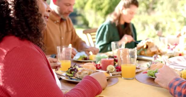 ハッピーな多様な男性と女性の友人が日当たりの良い庭で感謝祭の食事を食べています 愛国心 アメリカの文化と伝統 変わらない — ストック動画