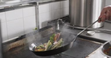 Kafkas erkek aşçı mutfakta tavada sebze kızartıyor, ağır çekimde. Aşçılık, meslek, yemek, restoran ve catering, değiştirilmemiş.