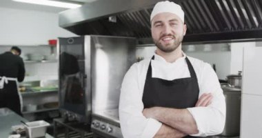 Beyaz erkek chet gülümsüyor ve kollarını mutfakta kavuşturuyor, ağır çekimde. Aşçılık, meslek, yemek, eğitim, öğretim, restoran ve yemek servisi, değiştirilmemiş.