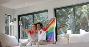 Gökkuşağı bayraklı çeşitli eşcinsel çiftler evde akıllı telefon kullanıyorlar, yavaş çekim, kopyalama alanı. Yaşam tarzı, lgbt, iletişim ve ev hayatı, değişmemiş..